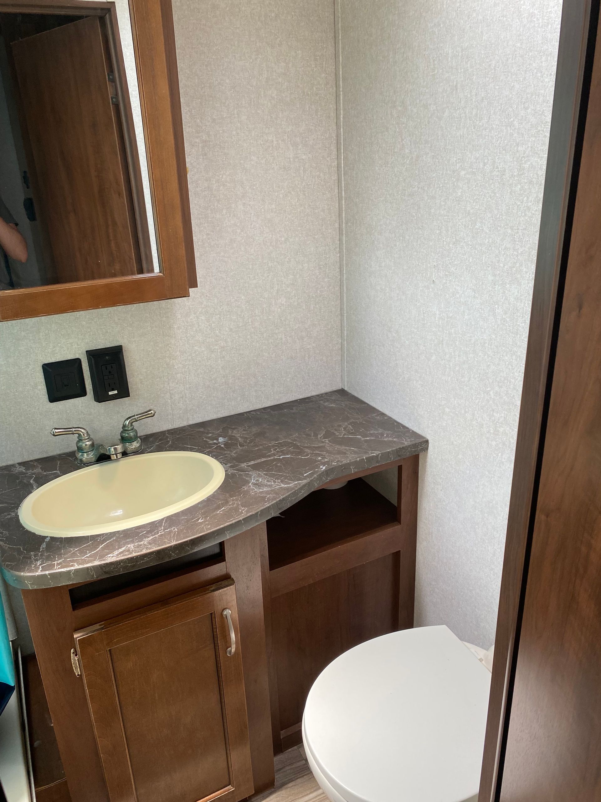 A bathroom with a sink and toilet and a mirror