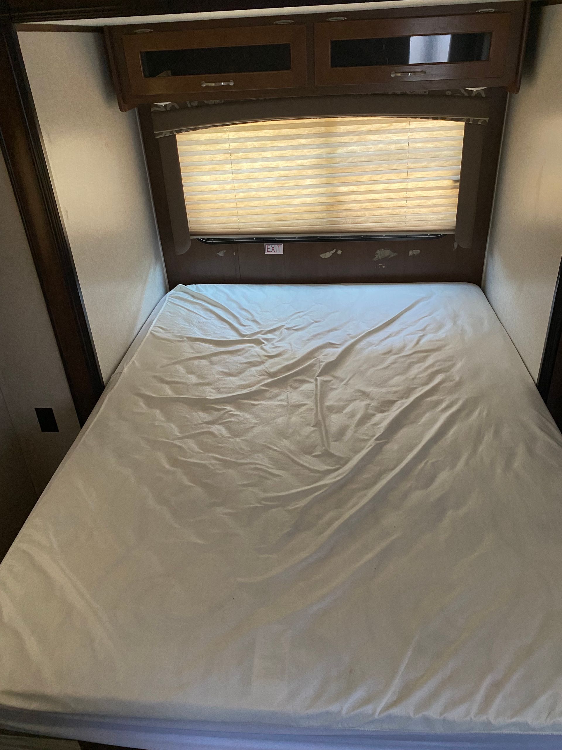 A bed with a mattress and a window in a rv.