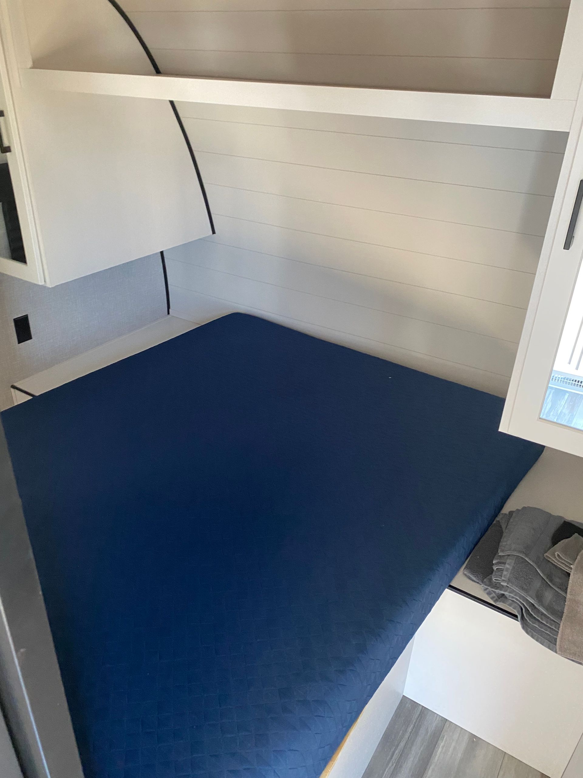 A bed with a blue mattress in a camper.