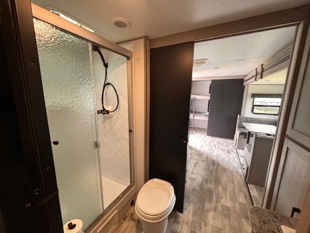 A bathroom with a toilet , shower and mirror.