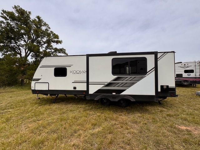 A white rv is parked in a grassy field