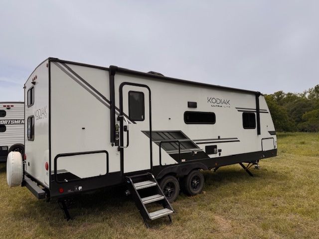 A white rv is parked in a grassy field.