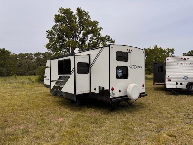 A white trailer is parked in a grassy field.