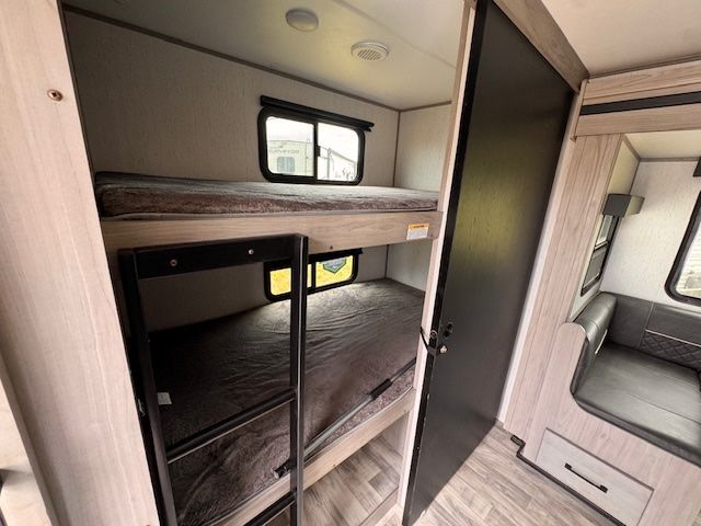 The inside of a rv with bunk beds and a refrigerator.