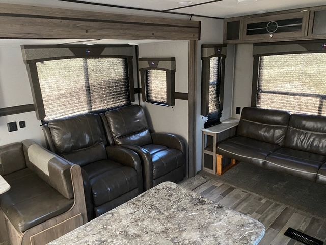 A living room in a rv with a couch , chairs , and a table.