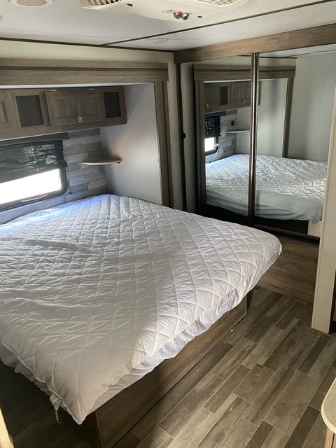 A bedroom in a rv with a bed and two mirrors.