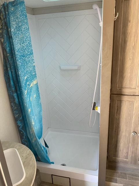 A bathroom with a shower and a blue shower curtain.
