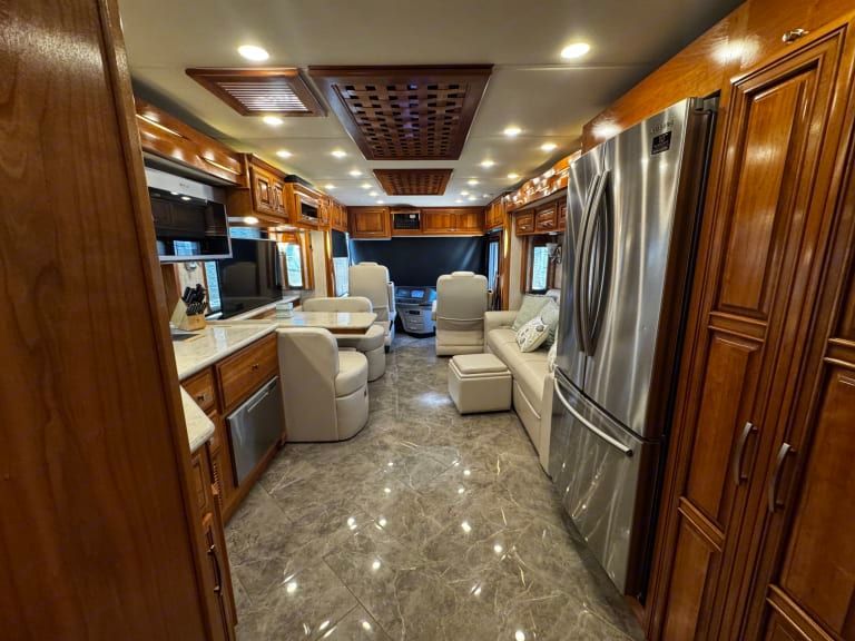 The inside of a rv with a stainless steel refrigerator and a couch.