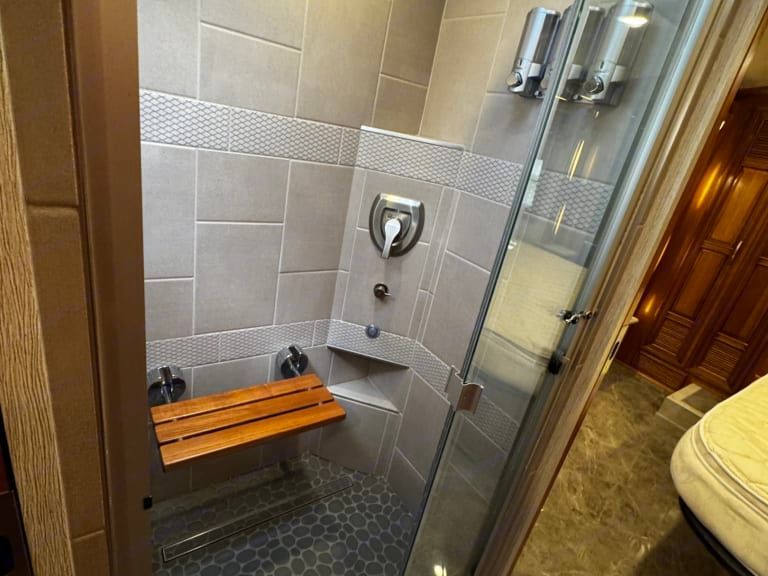 A bathroom with a walk in shower and a wooden bench.