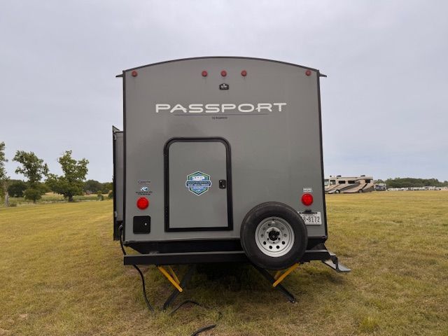 A passport trailer is parked in a grassy field.