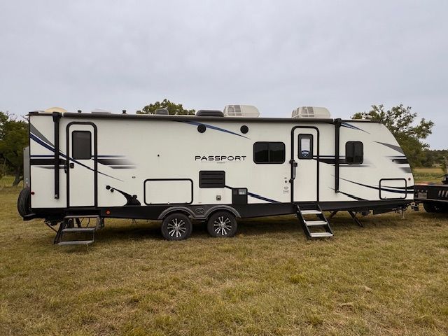 A passport trailer is parked in a grassy field.