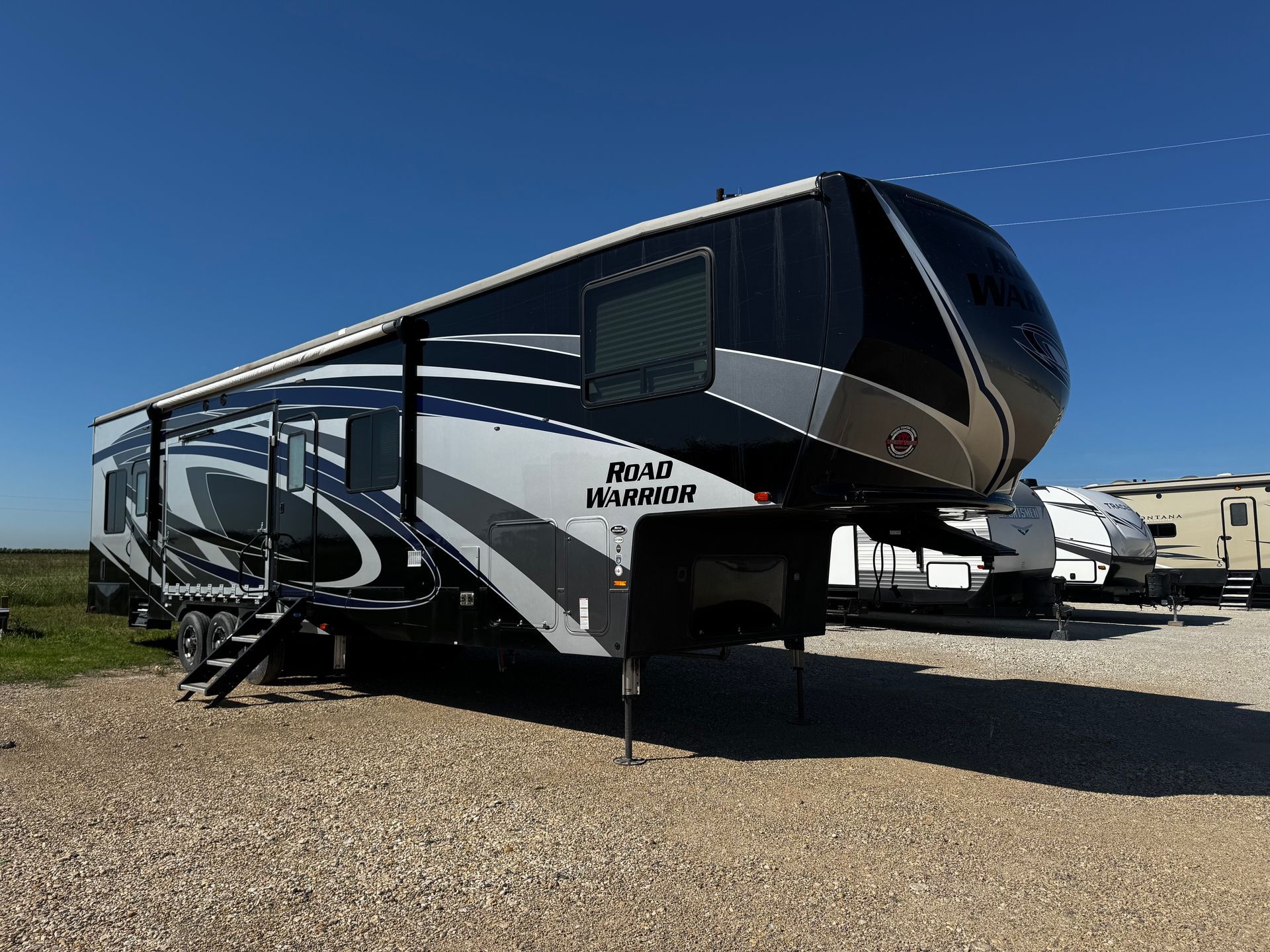 A black and white rv is parked in a gravel lot.
