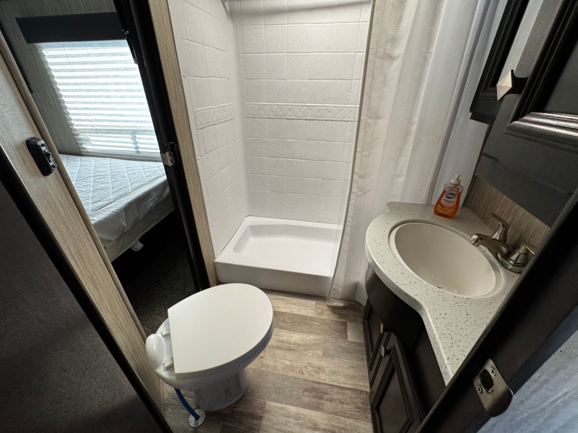 A bathroom with a toilet , sink , shower and mirror.