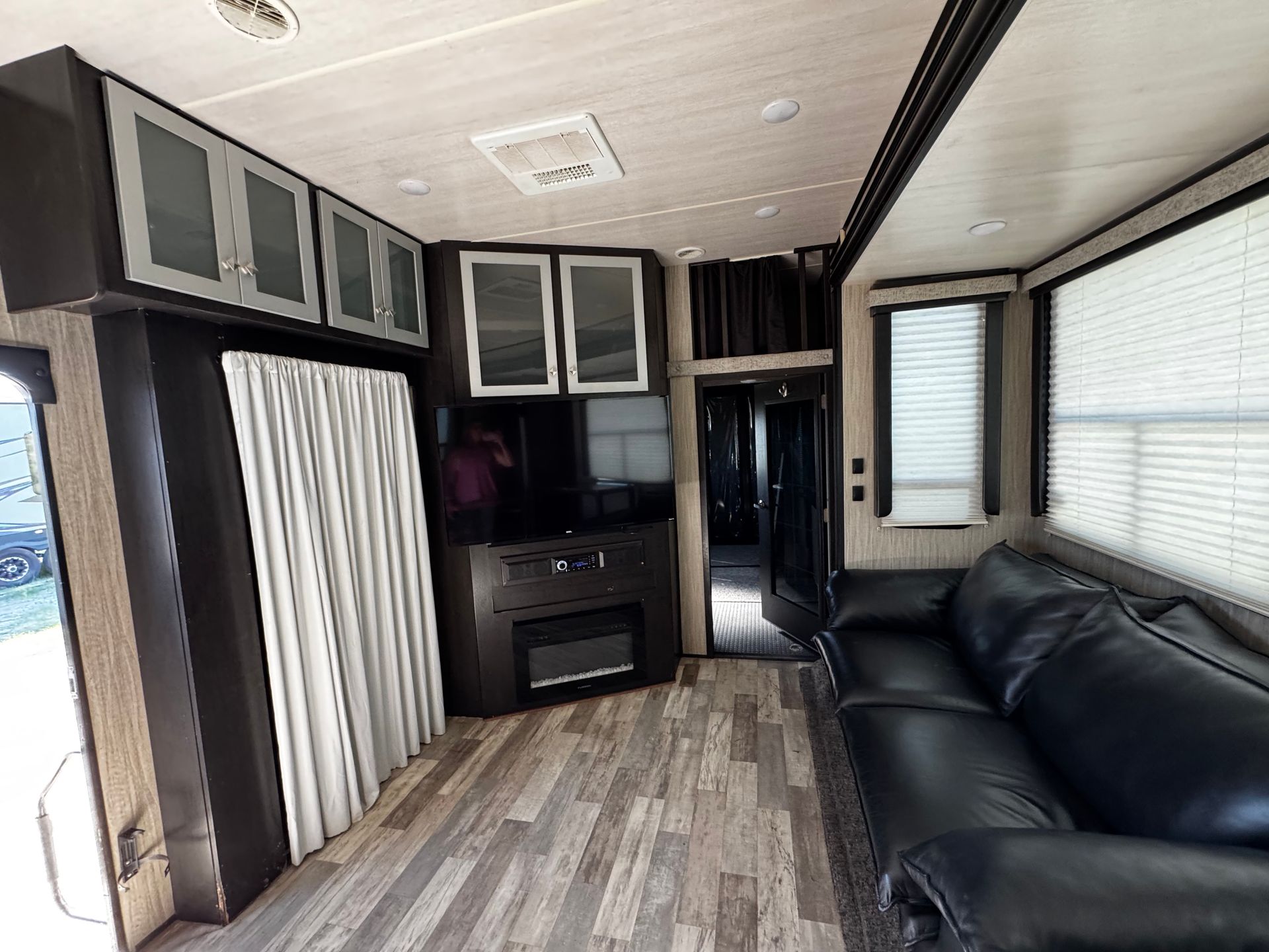 A living room in a trailer with a black couch and a flat screen tv.