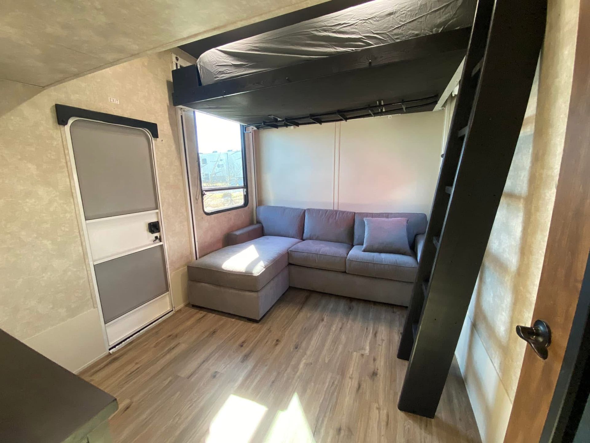 A living room with a couch , stairs , and a bunk bed.