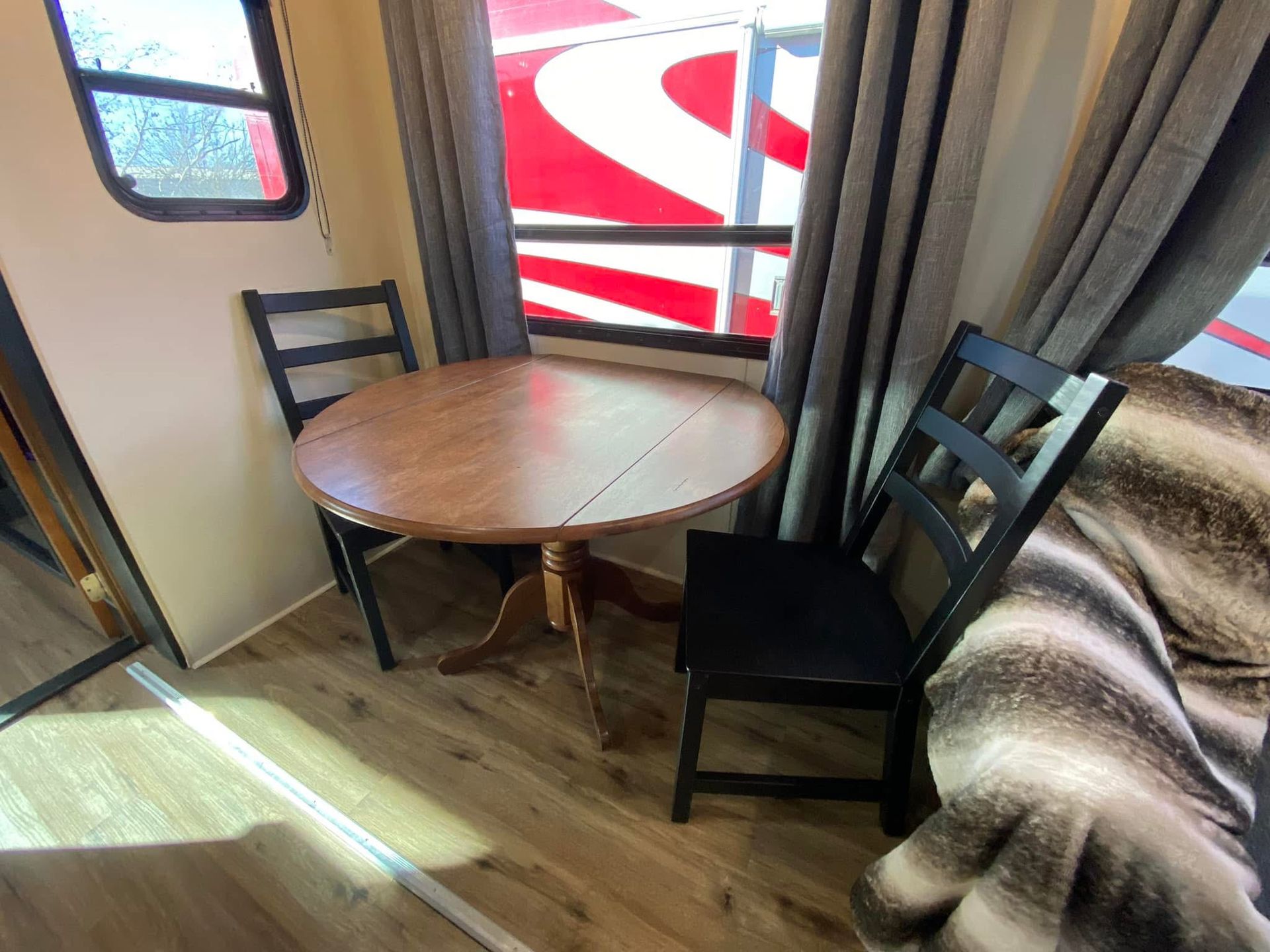 A room with a table and chairs in front of a window.