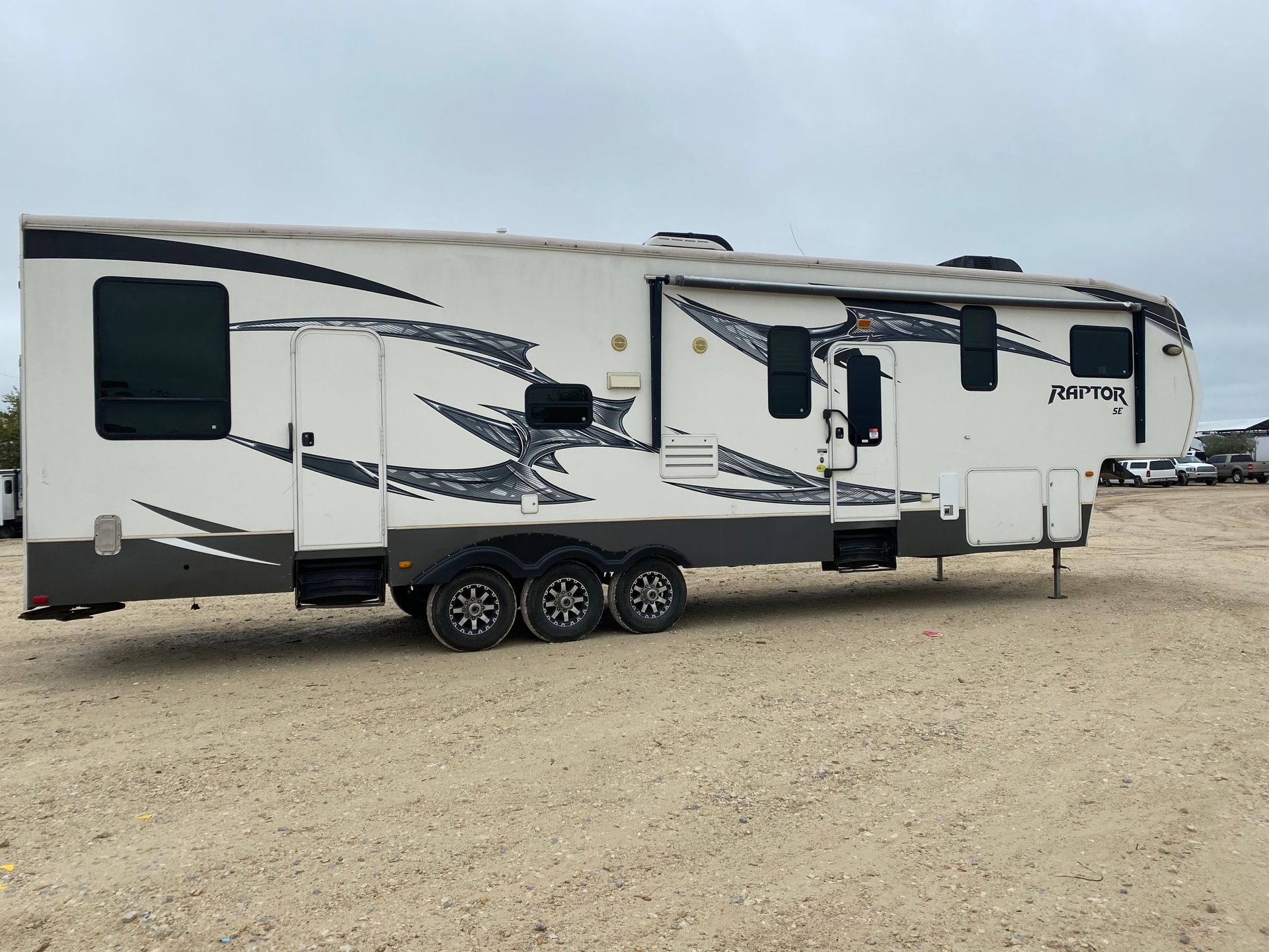 A white rv is parked in a dirt lot.