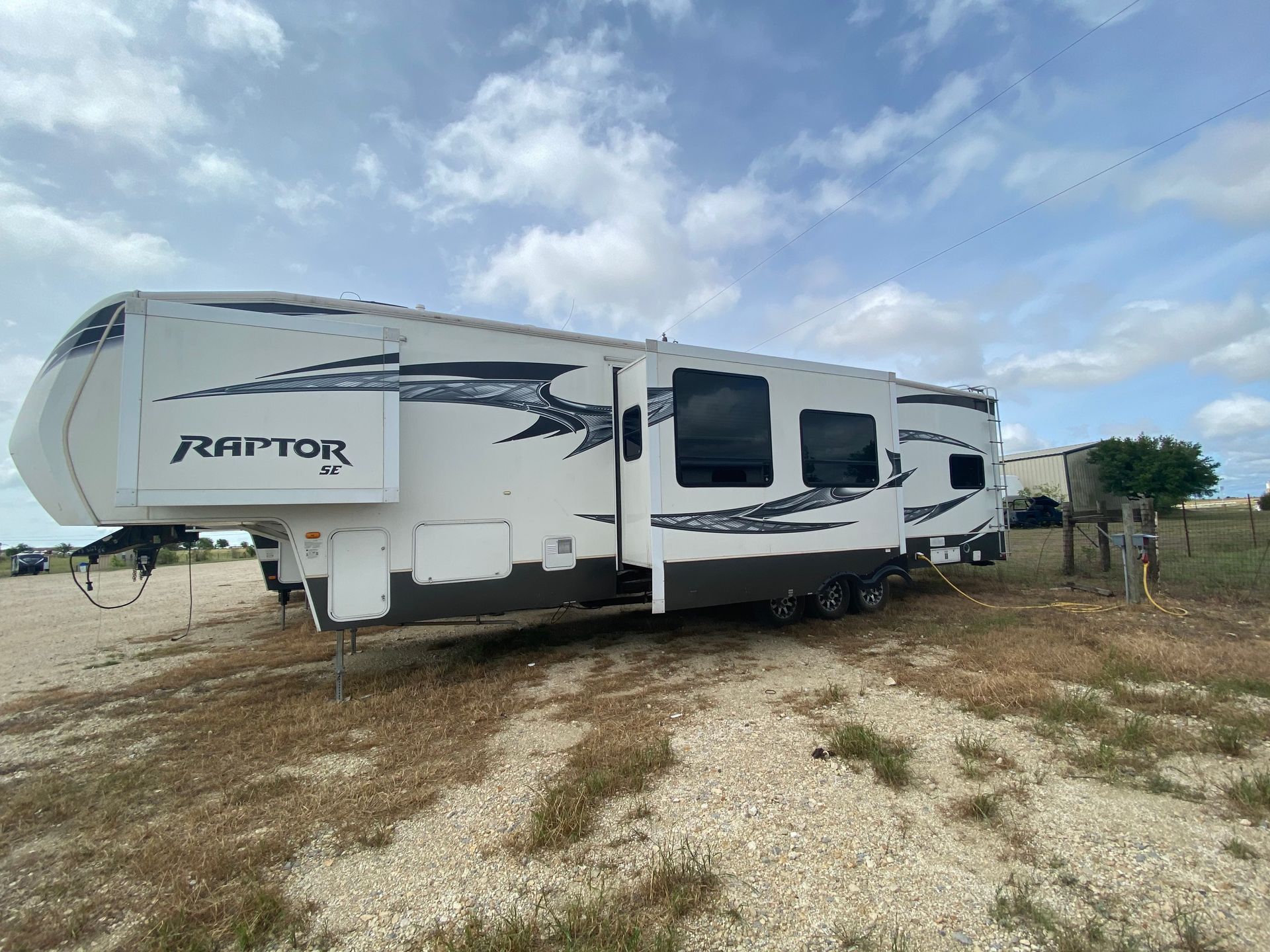 A white rv is parked in a gravel lot.