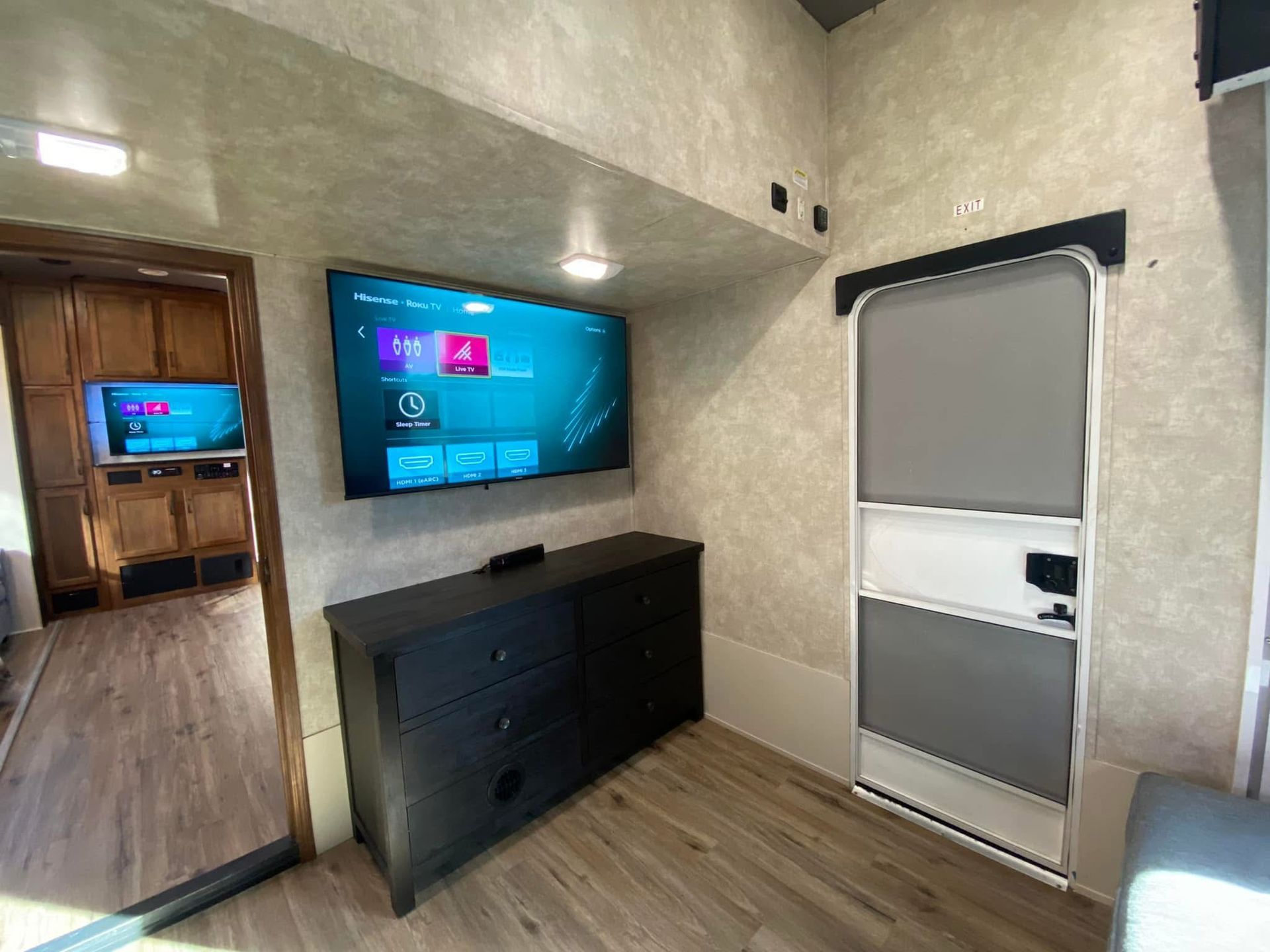 A room with a dresser and a flat screen tv on the wall.