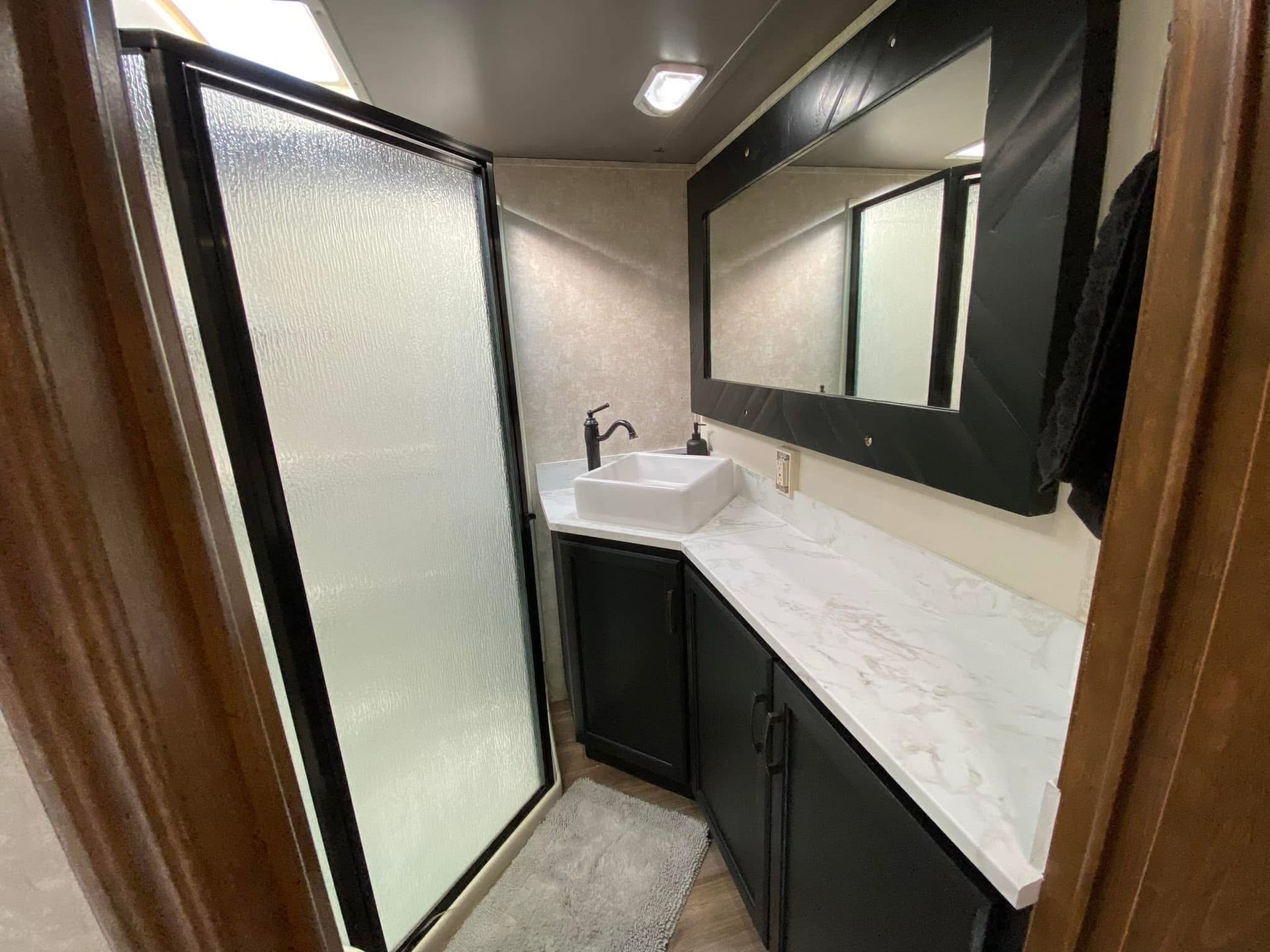 A bathroom with a sink , mirror and walk in shower.