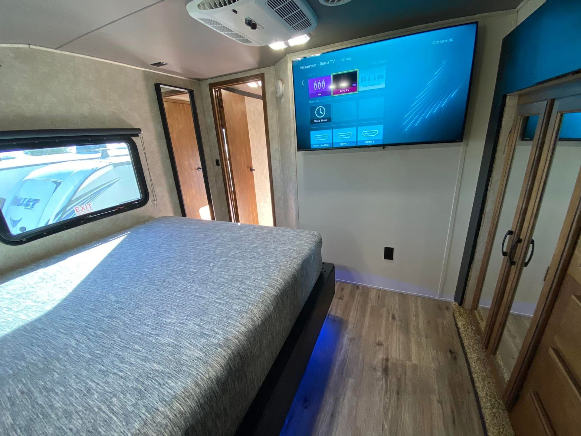 A bedroom in a rv with a bed and a flat screen tv on the wall.
