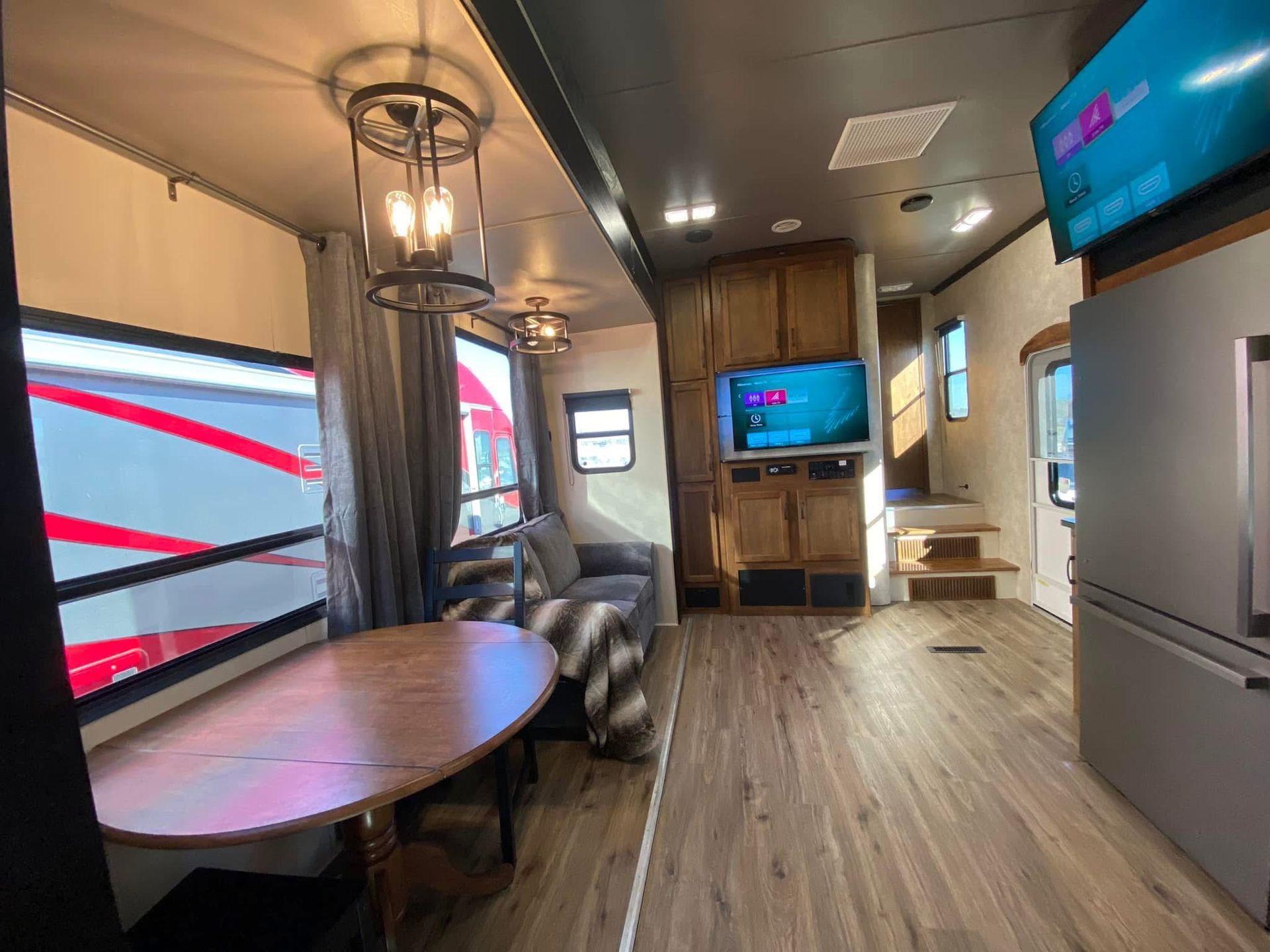A living room with a table , couch , television and refrigerator.