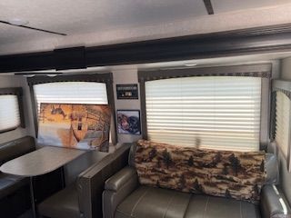 A living room in a rv with a couch , table and window.