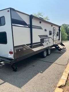 A white and brown trailer is parked on the side of the road.