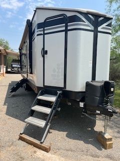 A white trailer with stairs attached to it is parked in a driveway.