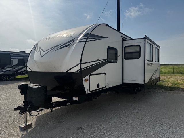 A white and black trailer is parked in a parking lot.