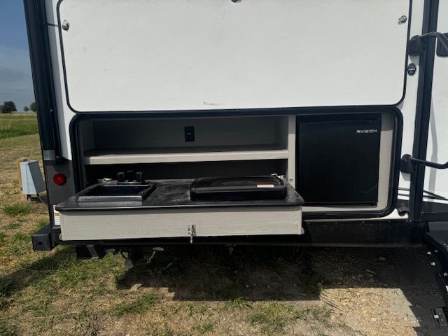 The back of a trailer with a sink and a refrigerator.