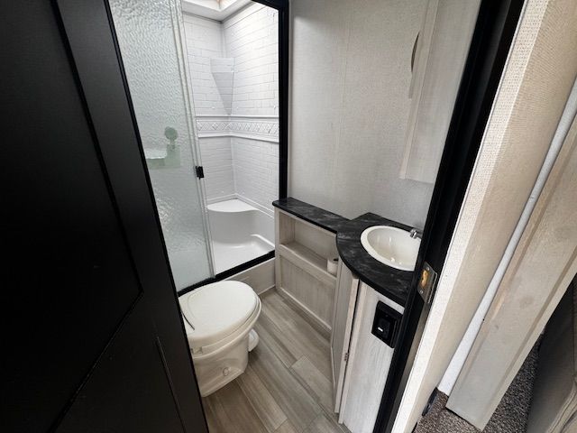 A bathroom with a toilet , sink and shower.
