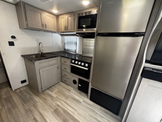 A kitchen with a refrigerator , stove , sink and microwave.