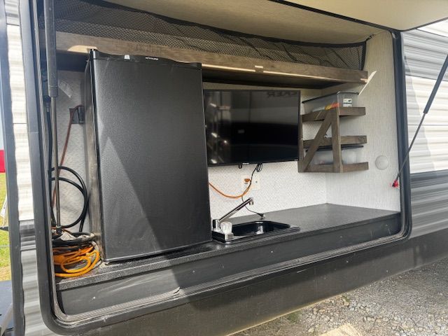 The inside of a trailer with a refrigerator , sink , and television.