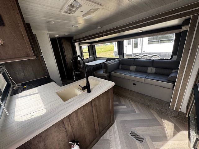 A kitchen with a sink and a couch in a trailer.