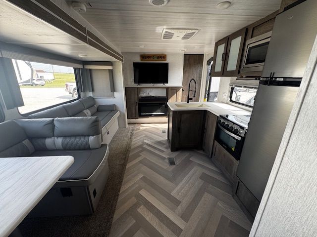 The inside of a rv with a couch , table , refrigerator and television.