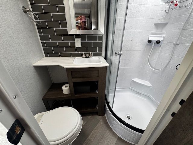 A bathroom with a toilet , sink and shower.