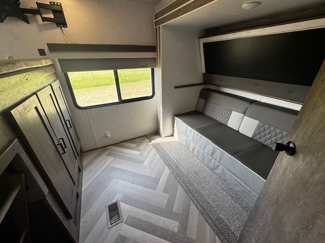 A room in a trailer with a couch and a window.