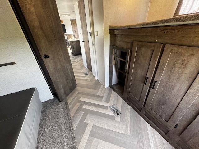 A hallway with wooden cabinets and a herringbone floor