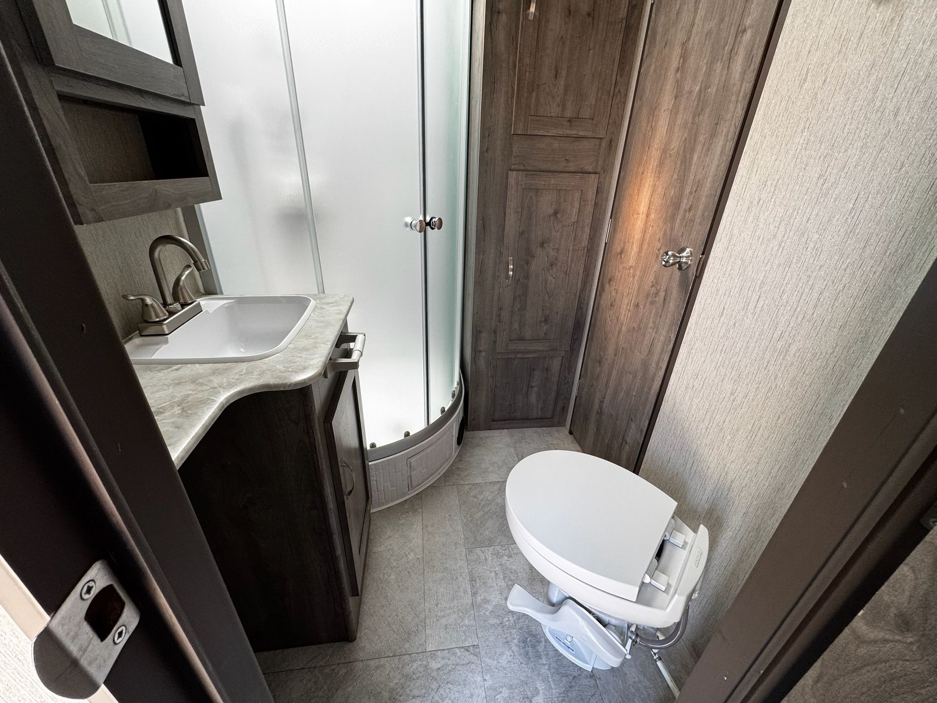 A bathroom with a toilet , sink and shower.