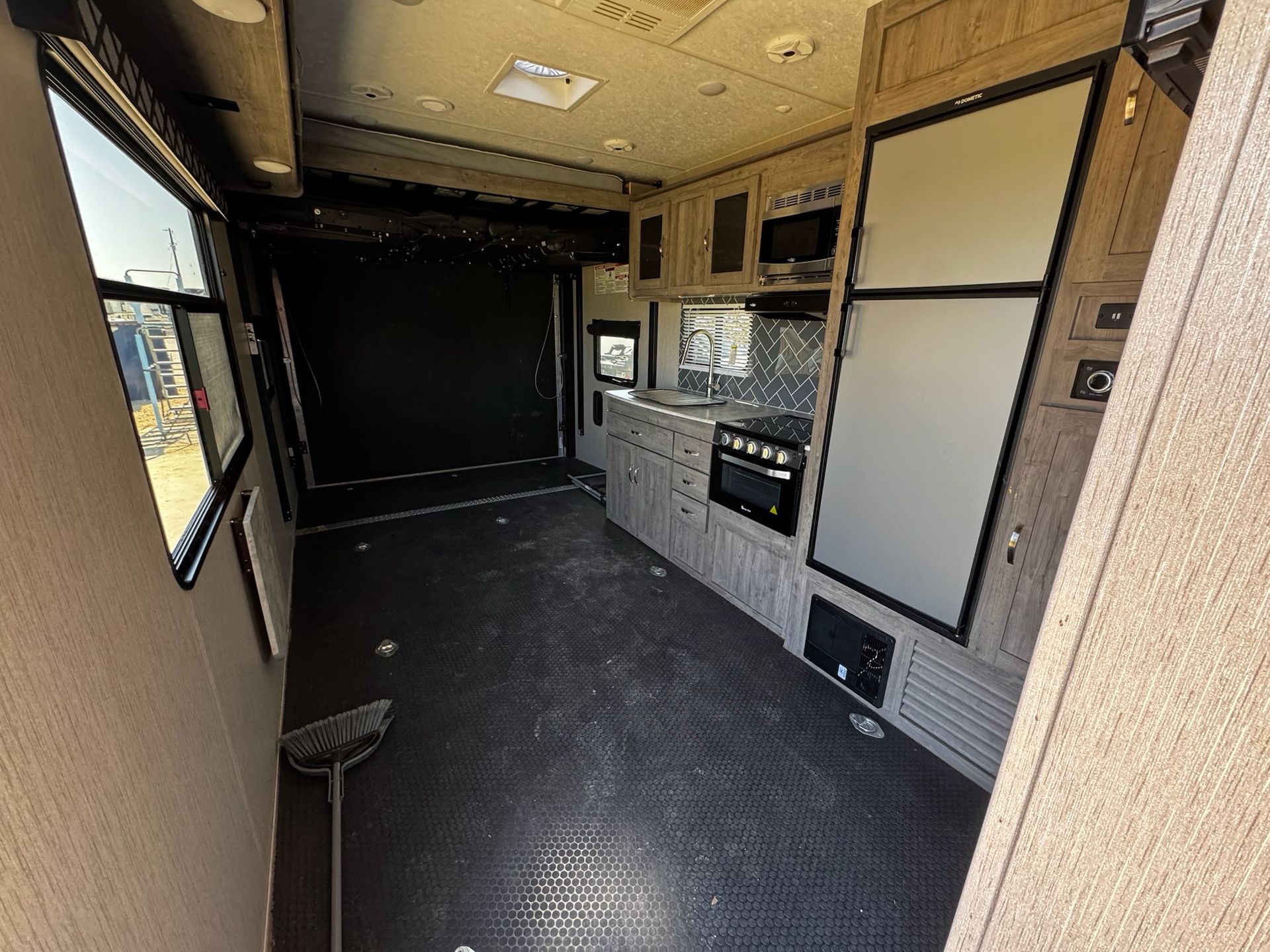 The inside of a trailer with a kitchen and a refrigerator.