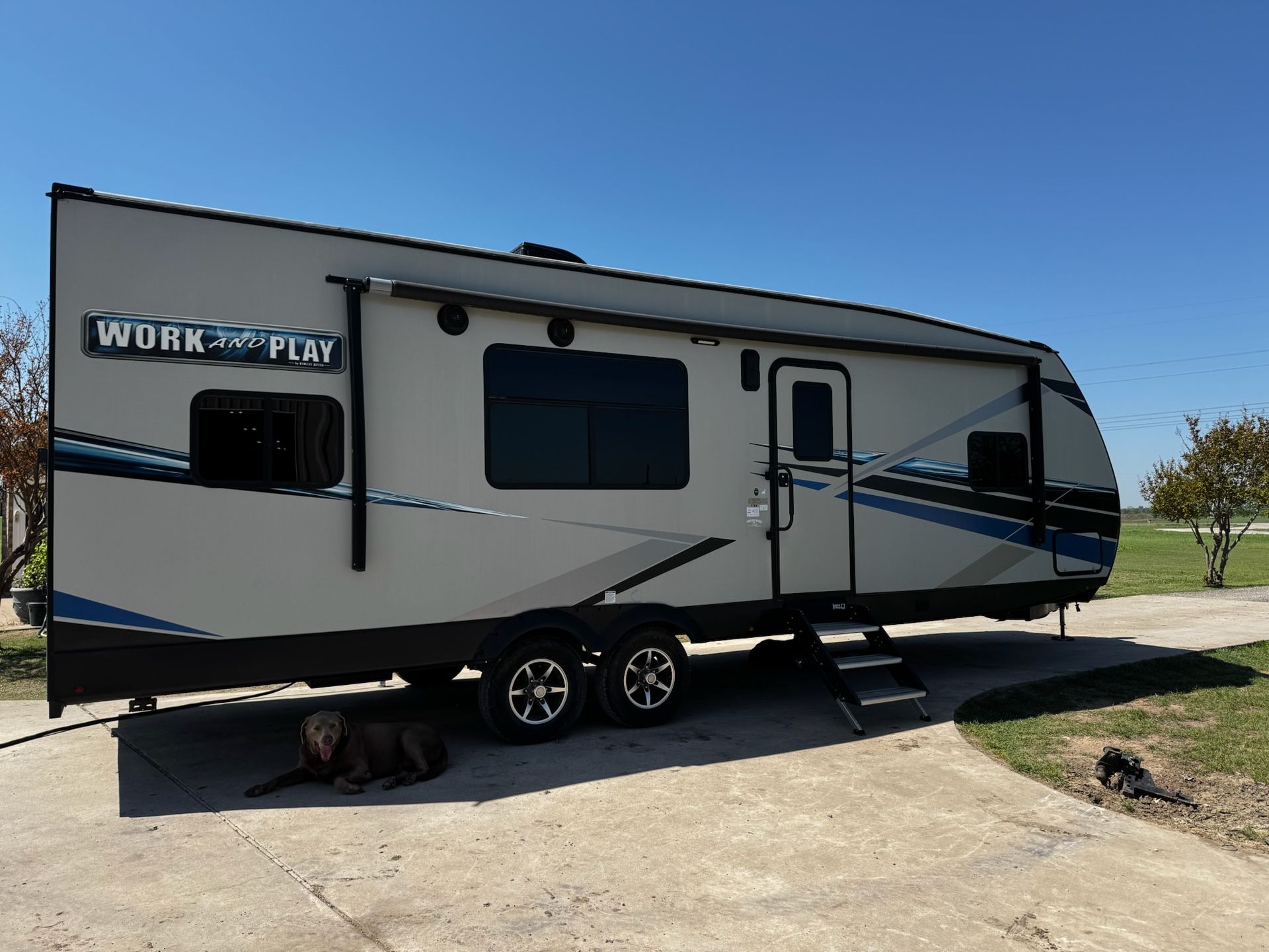 A work and play trailer is parked in a driveway