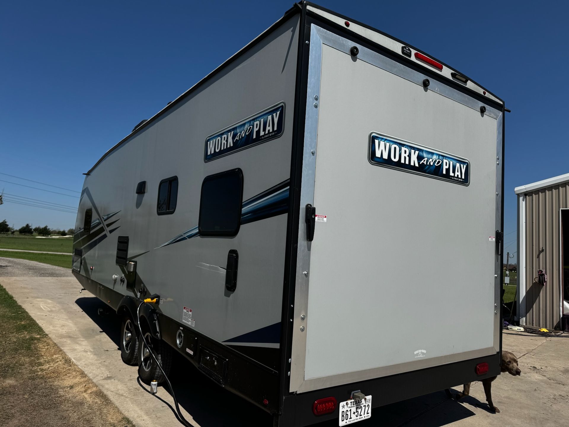 A work and play trailer is parked on the side of the road.