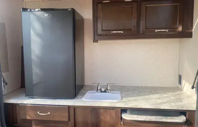 A kitchen with a sink , refrigerator and cabinets.