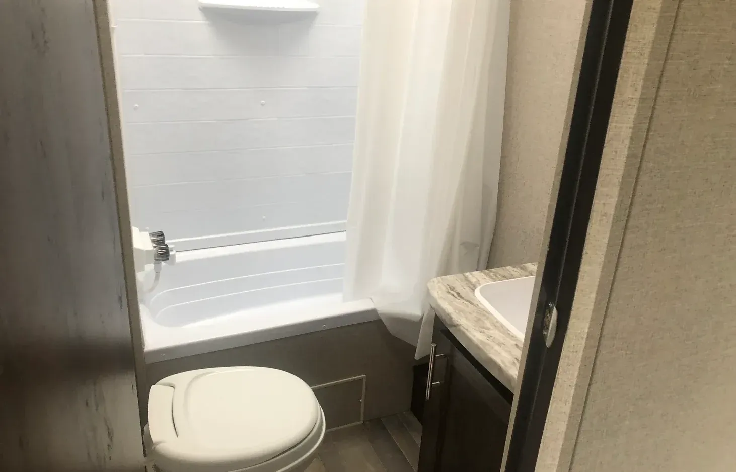 A bathroom with a toilet , tub and shower.