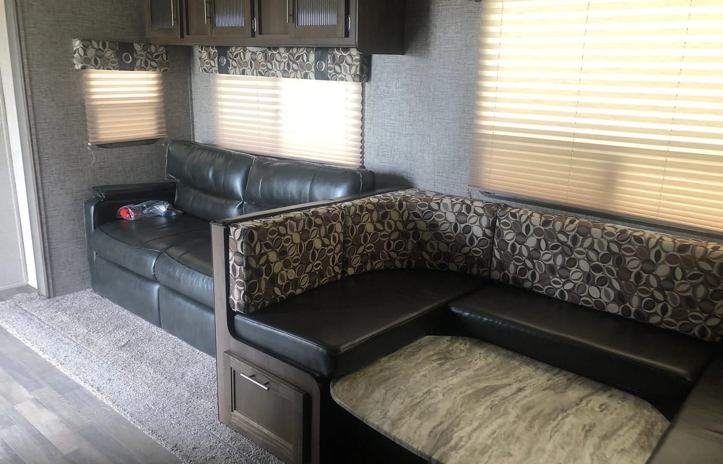A living room in a trailer with a couch and ottoman.