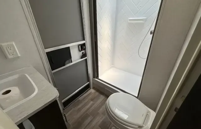 A bathroom with a toilet , sink and shower.