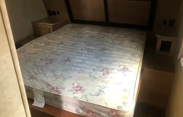 A bed with a mattress and a nightstand in a bedroom.