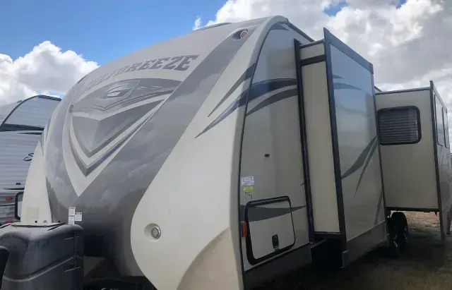 A white and gray rv is parked in a lot.