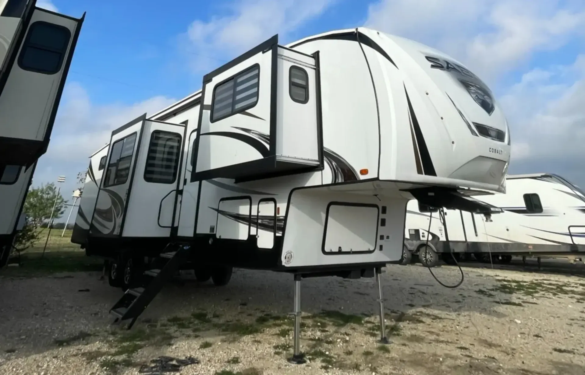 A white rv is parked in a gravel lot.